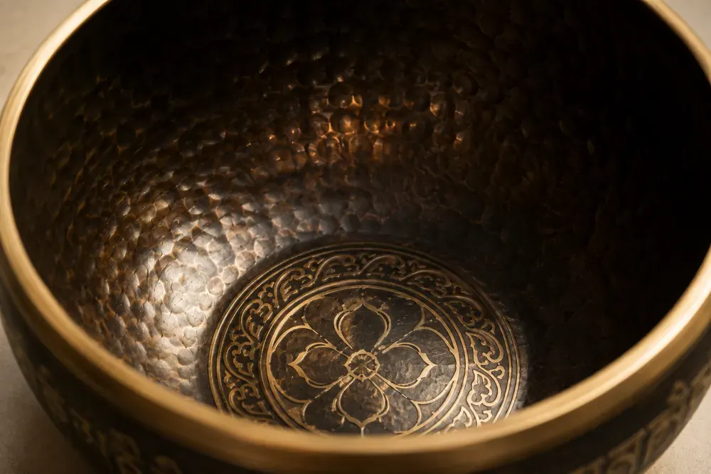 Close-up inside a singing bowl showing the hammered wall and the gold motif struck into the base