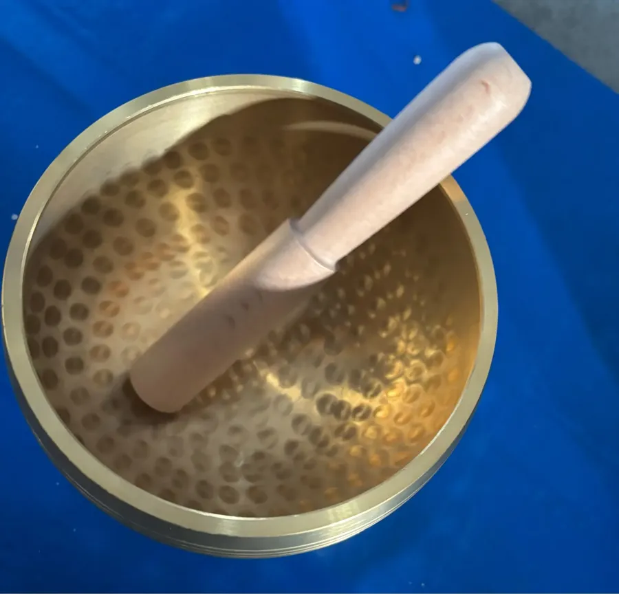 Verified buyer photo: top view of the hammered brass bowl with its wooden mallet resting inside