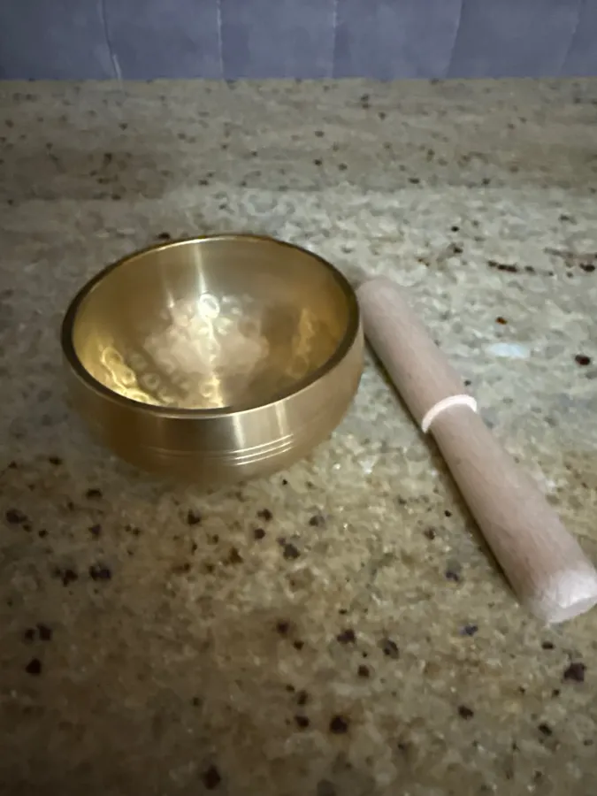 Verified buyer photo: compact 8 cm brass bowl beside its wooden mallet on a speckled stone counter