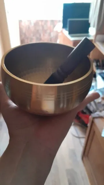 Verified buyer photo: the brass singing bowl held in one palm with the mallet inside