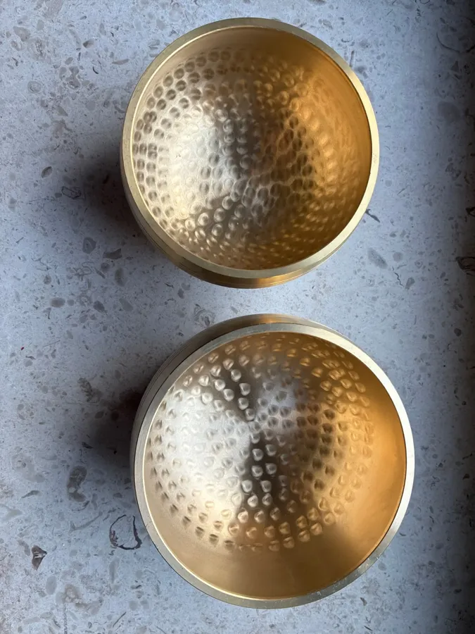 Verified buyer photo: two hammered brass singing bowls from the same order, photographed from above on a stone floor