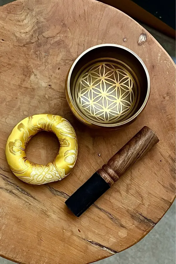 Verified buyer photo: the complete set laid out on a wooden stool — engraved bowl, gold silk cushion and double-ended mallet